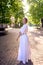 chic middle age woman in a white vintage dress in a sunlit alley