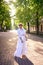 chic middle age woman in a white vintage dress in a sunlit alley