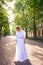 chic middle age woman in a white vintage dress in a sunlit alley