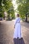 chic middle age woman in a white vintage dress in a sunlit alley