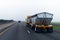 Chic new yellow truck with two bulk trailers on straight as arrow highway in fog