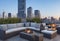 A chic rooftop terrace with lounge furniture, a fire pit, and panoramic views of the city skyline