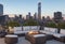 A chic rooftop terrace with lounge furniture, a fire pit, and panoramic views of the city skyline