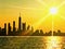 Chicago skyline seen from Lake Michigan, with sunset and sunbeams extending over cityscape during summer