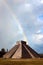 Chichen Itza archaeological complex in Mexico against the sky with clouds and a rainbow.