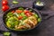 Chicken breast and avocado salad with spinach, tomatoes and Caesar dressing, dark background.