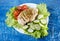 Chicken breast with herbs, tomatoes and cucumbers on blue background