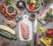 Chicken breast preparation with various vegetables and ingredients for tasty diet cooking on gray concrete background, top view, f