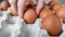 Chicken brown eggs in paper packaging. Close-up. Hand of Caucasian girl takes one egg. Shooting on bright day, daylight from