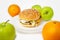 Chicken burger next to many apples and oranges