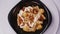 Chicken and cheese pasta with tomato on a black plate rotates in a circle