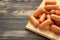 Chicken cocktail sausage on cutting board on brown wooden background. Space for text