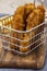 Chicken coujons coated in breadcrumbs in a wire metal basket, with fries