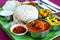 Chicken curry thali served with dry potato and caulifower curry rasam curd and papad