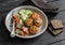 Chicken cutlets and fresh vegetable salad on ceramic plate on dark wooden background.