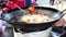 Chicken drummets deep frying in oil in a cast iron frying pan