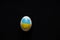 Chicken egg with the flag of Ukraine on a black background. Ukraine during the war, protests, no war, peace in Ukraine