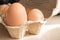 Chicken eggs in cardboard box. Giant egg with eggs of usual size. Fresh yellow eggs in sunlight. Healthy organic food.