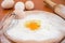 Chicken eggs, flour, whisk and rocking chair on the table. The process of making dough. Close-up. Broken egg in flour on a wooden