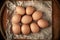 Chicken eggs. Top view of a group of raw brown chicken eggs on crumpled wrapping paper on a wooden surface. High calorie protein