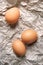Chicken eggs. Top view of three raw brown chicken eggs on crumpled wrapping paper. High calorie protein food concept