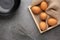 Chicken eggs on the wooden tray, egg beater and black glass bowl.