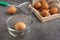 Chicken eggs on the wooden tray, egg beater and glass bowl.