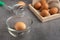 Chicken eggs on the wooden tray, egg beater and glass bowl.