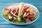 Chicken fajitas with grilled onions and bell peppers and tortillas on blue wooden table