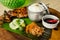 Chicken Inasal served with Garlic Rice, cucumber and Atchara. On a banana leaf on top of wooden platter.