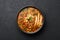 Chicken Manchow Soup in black bowl at dark slate background. Chicken Manchow Soup is indo-chinese cuisine dish