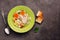 Chicken noodle soup, potatoes, carrots in a green plate served with fried toasts on a dark rustic background. Top view, copy space