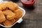 chicken nuggets in a food delivery box with white and red sauce on a brown wooden background. fast food close-up