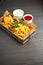 Chicken nuggets with french fries and different sauces on wooden board,