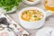 Chicken orzo soup in a white crock on wooden background. Italian soup with orzo pasta
