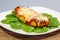 Chicken Parmesan on a bed of spinach with a sprinkle of fresh parmesan cheese on top on a white plate