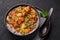 A Chicken Patiala in black bowl on dark slate table top. Murg Patiala is indian cuisine curry dish. Asian food and meal