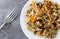 Chicken with pecans and wild rice on a plate with a fork to the side on a gray background top view