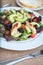 Chicken salad with avocado, mixed greens, cucumbers, tomatoes, and olives.
