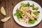 Chicken salad, pears, dried gooseberries and currants, cheese on basil leaves. Wooden background. Top view. Close-up