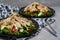 Chicken salads with avocado, rucola and cherry tomatoes in a black plate on gray stone background