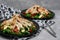 Chicken salads with avocado, rucola and cherry tomatoes in a black plate on gray stone background.