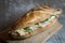 Chicken sanwdich with cream cheese in a French baguette, with some slices of rucola salad and chicken dressing