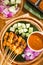 Chicken sate with delicious peanut sauce, ketupat, onion and cucumber