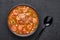 Chicken and Sausage Gumbo soup in black bowl on dark slate backdrop. Gumbo is louisiana cajun cuisine soup with roux. American USA