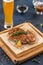 Chicken schnitzel grilled on wooden board with glass of beer on blue background