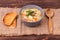 Chicken soup with noodles, vegetables and parsley leaves in a bowl served with slices of toast on a textured burlap