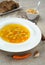 Chicken soup with vegetables in white bowl with croutons crackers and bread pepper on tablecloth.