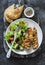 Chicken souvlaki kebabs, sun dried olives, tomatoes, cucumbers green salad and focaccia tortilla on dark background, top view