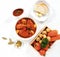 Chicken stew and bread with butters in white bowl, vegetable in a wooden box put down beside on white table, top view.